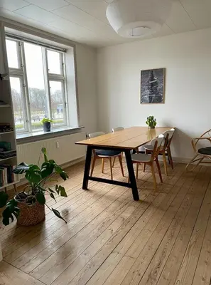 a dining room with a wooden table and chairs at Lejlighed midt i Thisted in Thisted