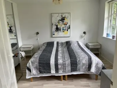 a bedroom with a bed with a black and white comforter at Idyllic Countryside Farm with Horseback Riding in Nibe