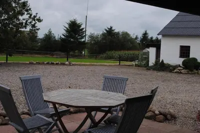 a wooden table and chairs in a yard at Idyllic Countryside Farm with Horseback Riding in Nibe
