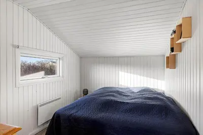 a bedroom with a blue bed in a room with a window at 822-Harboore-Neerlandiavej-138 in Harboør