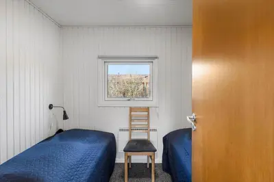 a bedroom with a bed and a chair and a window at 822-Harboore-Neerlandiavej-138 in Harboør