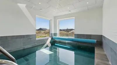 a swimming pool with blue seats in a room with windows at Villavilla 607 - Vorupør, Nordjylland in Thisted