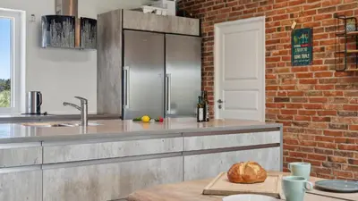 a kitchen with a counter with a refrigerator and a brick wall at Villavilla 607 - Vorupør, Nordjylland in Thisted