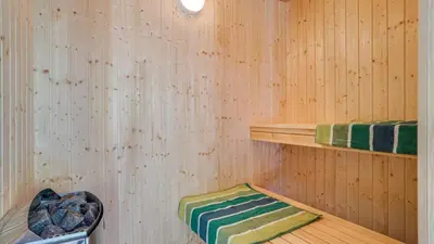 a sauna with wooden walls and a green and white rug at Villavilla 494 - Thorup Strand, Nordjylland in Fjerritslev