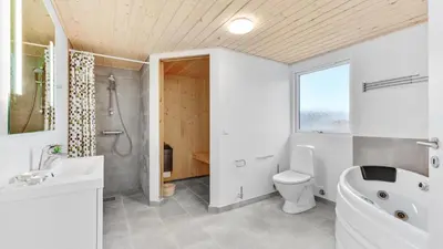 a bathroom with a tub and a toilet and a sink at Villavilla 539 - Hostrup Strand, Limfjorden in Spottrup