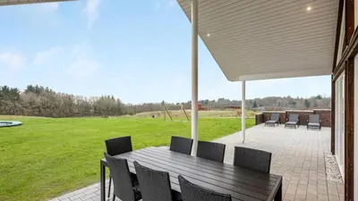 a patio with a wooden table and chairs at Villavilla 539 - Hostrup Strand, Limfjorden in Spottrup