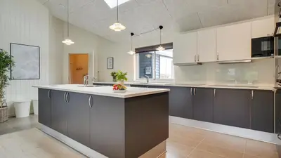 a large kitchen with white cabinets and a sink at Villavilla 429 - Hostrup Strand, Limfjorden in Spottrup