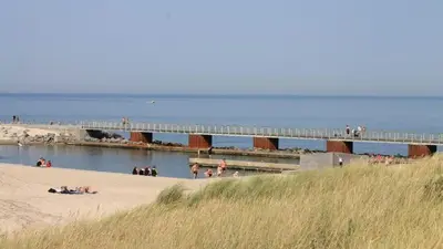 people on a beach with a bridge in the water at Villavilla 476 - Vorupør, Nordjylland in Thisted