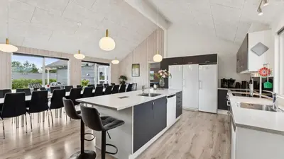 a kitchen with black chairs and a kitchen island at Villavilla 404 - Hostrup Strand, Limfjorden in Spottrup