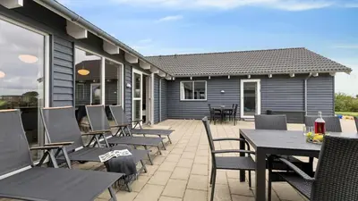 a patio with chairs and tables and a house at Villavilla 404 - Hostrup Strand, Limfjorden in Spottrup