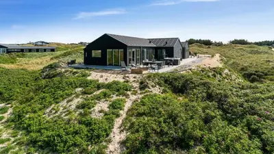 a black house on top of a grassy hill at Villavilla 514 - Grønhøj, Nordjylland in Løkken