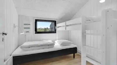 a bedroom with a bed with white walls and a window at Villavilla 909 - Blokhus, Nordjylland in Blokhus