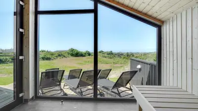 a group of chairs sitting on a porch with windows at Villavilla 909 - Blokhus, Nordjylland in Blokhus