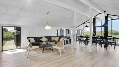 a living room with a couch and tables and chairs at Villavilla 909 - Blokhus, Nordjylland in Blokhus