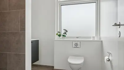 a bathroom with a toilet and a mirror at Villavilla 645 - Hostrup Strand, Limfjorden in Spottrup