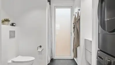 a white bathroom with a toilet and a television at Villavilla 683 - Blokhus, Nordjylland in Saltum