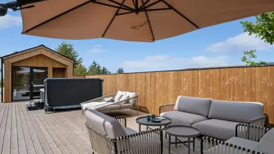 a patio with a couch and a tv and an umbrella at Villavilla 683 - Blokhus, Nordjylland in Saltum