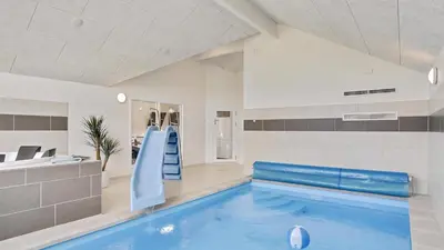 a swimming pool with a slide in a room at Villavilla 405 - Hostrup Strand, Limfjorden in Spottrup