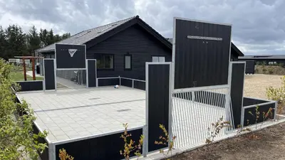 a black house with a tennis court in front of it at Villavilla 686 - Hostrup Strand, Limfjorden in Spottrup