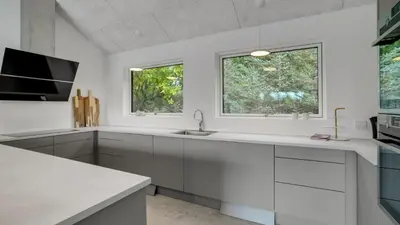 a white kitchen with a sink and two windows at Villavilla 692 - Blokhus, Nordjylland in Blokhus