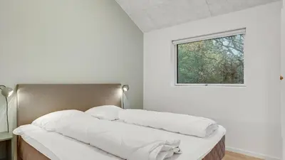 a bed with white pillows in a room with a window at Villavilla 692 - Blokhus, Nordjylland in Blokhus