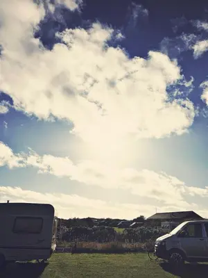 a white van parked in a field under a cloudy sky at Bovbjerg Camping in Lemvig