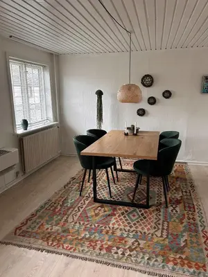 a dining room with a table and chairs on a rug at Villa With Three Bedrooms in Vemb