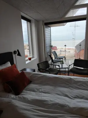 a bedroom with a bed and a balcony with chairs at Hotel og Restaurant Havbadet in Thisted
