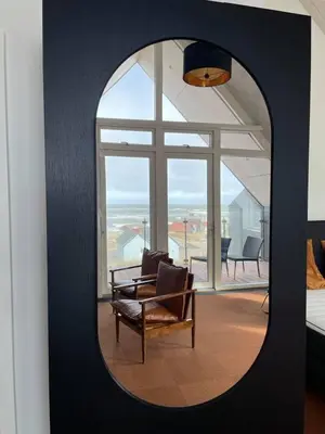 a mirror in a room with a chair and a window at Hotel og Restaurant Havbadet in Thisted