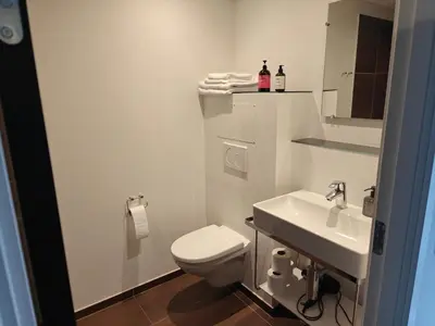 a white bathroom with a toilet and a sink at Hotel og Restaurant Havbadet in Thisted