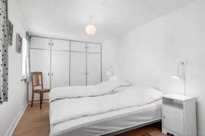a white bedroom with a bed and a chair at 730-Thyboron-Manovej-9 in Thyborøn