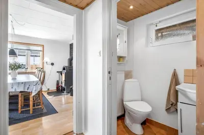 a bathroom with a toilet and a kitchen with a table at 730-Thyboron-Manovej-9 in Thyborøn
