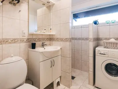 a bathroom with a toilet and a sink and a washing machine at 5 star holiday home in Saltum in Saltum