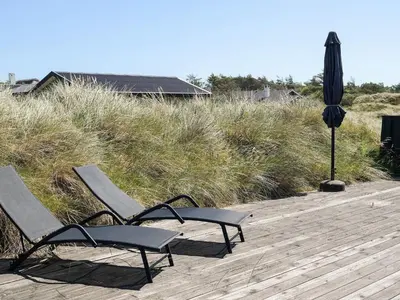 two chairs and an umbrella on a wooden deck at 5 star holiday home in Saltum in Saltum