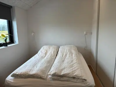 a unmade bed in a room with a window at Luxury cottage close to the beach in Løkken
