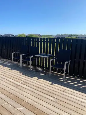 a table and chairs on a deck with a fence at Luxury cottage close to the beach in Løkken