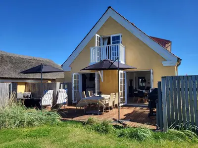 a house with a patio with chairs and umbrellas at Strandhuset in Agger