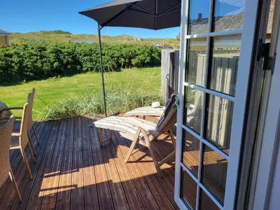 a patio with an umbrella and chairs on a deck at Strandhuset in Agger
