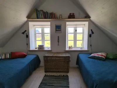 a attic room with two beds and two windows at Strandhuset in Agger