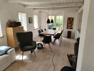 a living room with a dining room table and chairs at Strandhuset in Agger