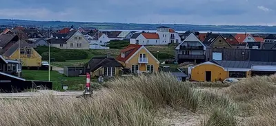 a town with houses on a hill with tall grass at Strandhuset in Agger