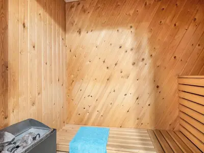 a sauna with a wooden wall with a bed in it at Holiday Home Siljana - 200m from the sea by Interhome in Lemvig