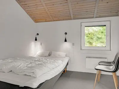 a white bedroom with a bed and a chair at Holiday Home Nimrod - 70m from the sea by Interhome in Thisted