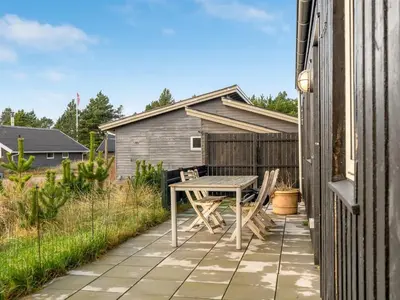 a patio with a table and chairs on the side of a house at Holiday Home Ovine - 900m from the sea by Interhome in Thisted