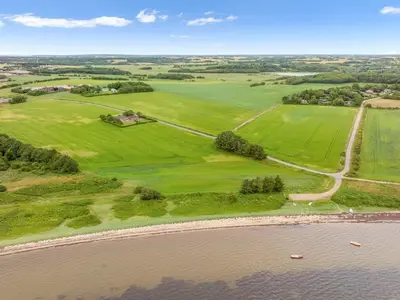 an aerial view of green fields next to a river at Holiday Home Erja - 300m to the fjord by Interhome in Roslev