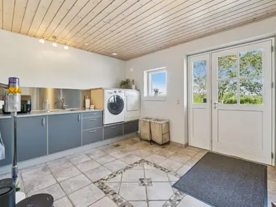 a kitchen with a washer and dryer in it at Holiday Home Fridhild - 150m to the fjord by Interhome in Redsted