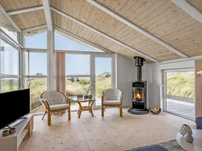 a living room with a fireplace and a table and chairs at Holiday Home Osfrid - 175m from the sea by Interhome in Blokhus