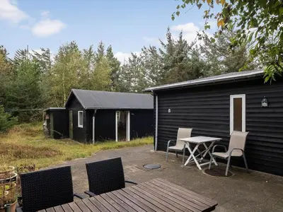a patio with a table and chairs and a building at Holiday Home Patti - 700m from the sea by Interhome in Blokhus
