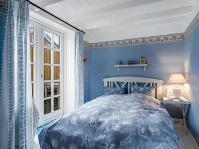 a blue bedroom with a bed and a window at Holiday Home Åsta - 200m from the sea by Interhome in Saltum