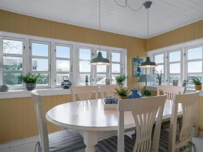 a dining room with a white table and chairs at Holiday Home Åsta - 200m from the sea by Interhome in Saltum